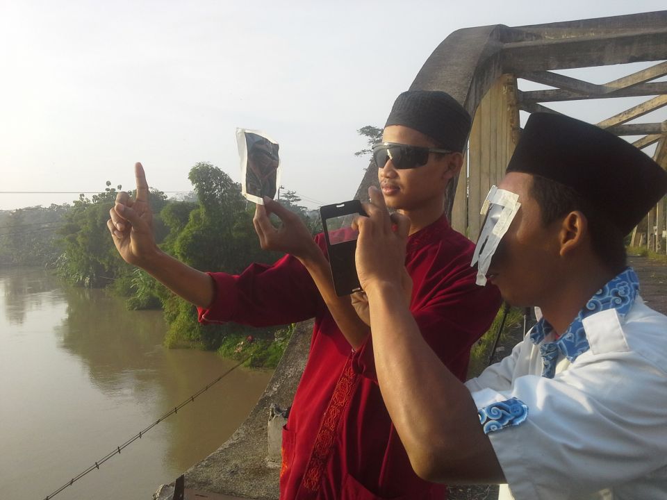 Sejumlah santri berhenti sejenak untuk melihat proses gerhana matahari di Jembatan Soeharto Rawalo Banyumas sebelum melakukan sholat gerhana, Rabu (9/3). (Aris Andrianto/Purwokertokita.com)